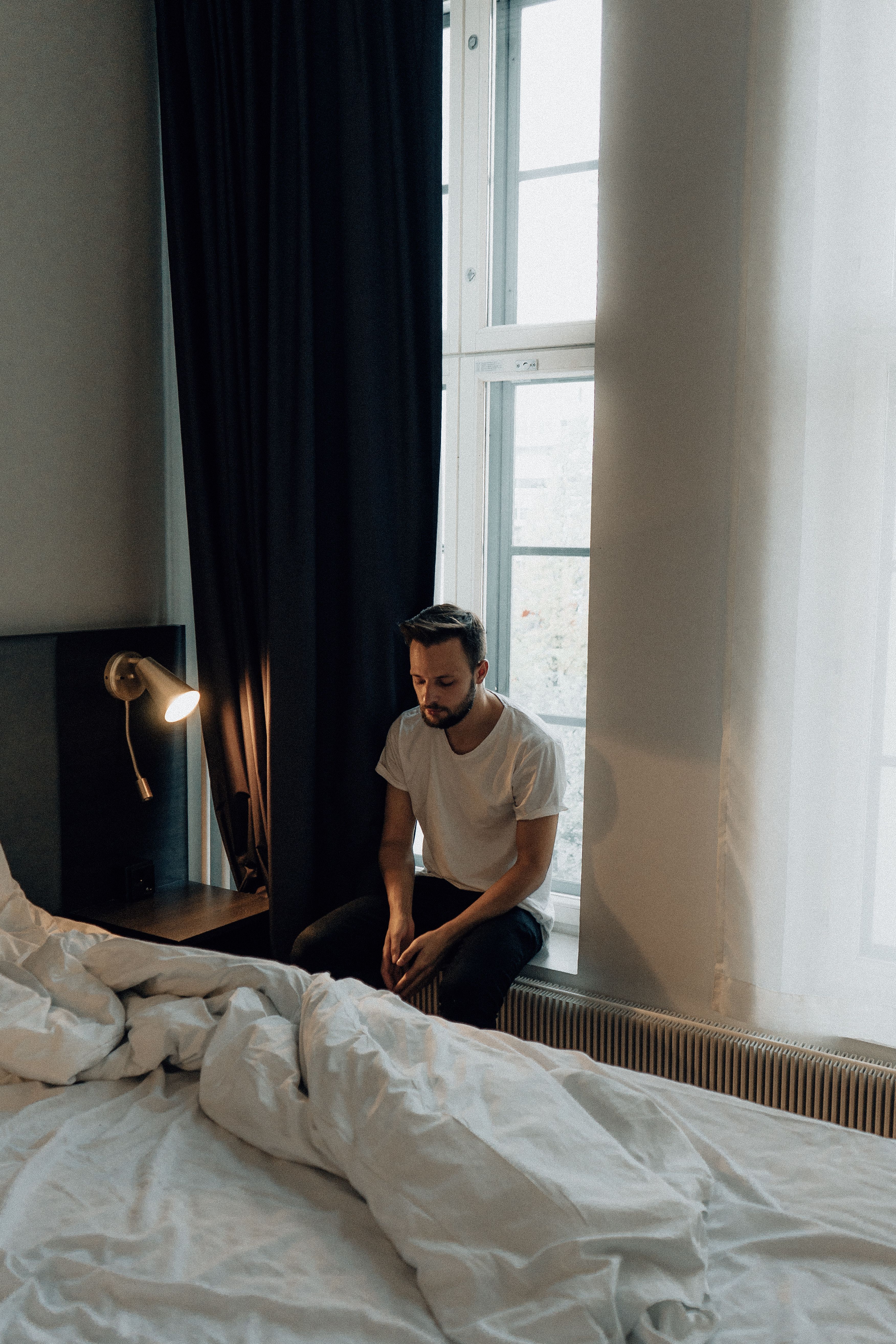 Mann sitzt nachdenklich am Fenster, emotionale Taubheit und innere Leere
